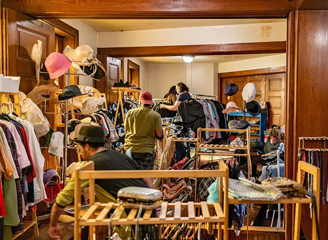 The inside of a Skylight Boutique event. An assortment of colorful, clothes, hats and purses are spread around the room.