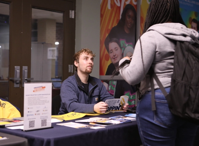 A recruiter for Coppin answers a CCBC student's questions at the college's transfer fair table.