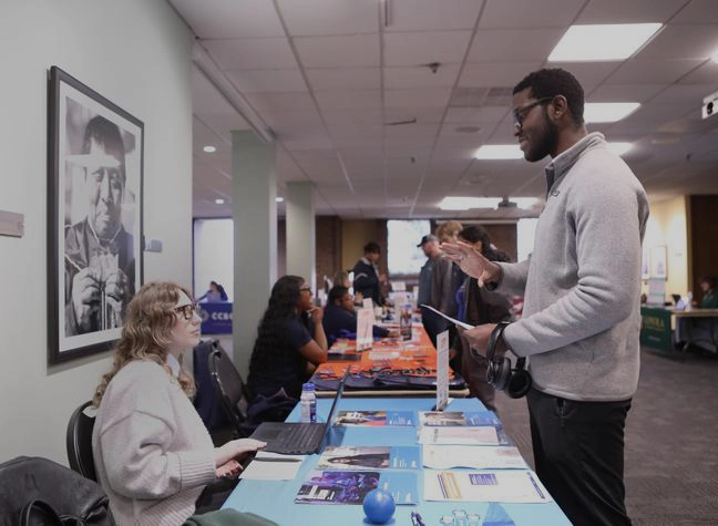 A student asks an admission recruiter questions at their Transfer Fair table.