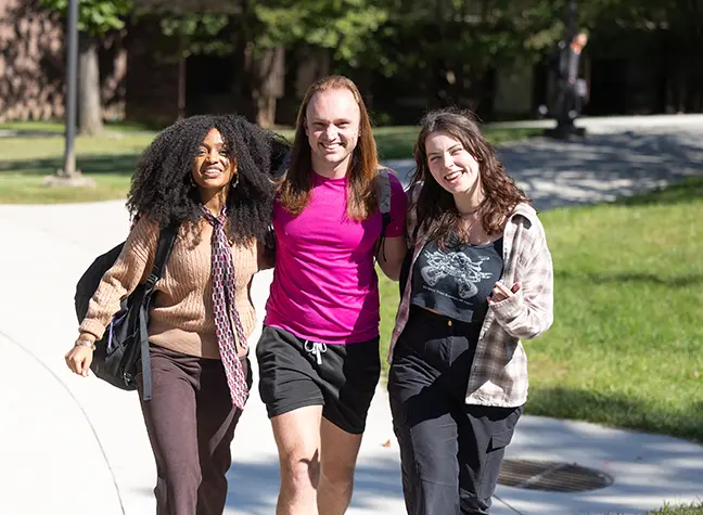 Three students on their way to class, walking outside.