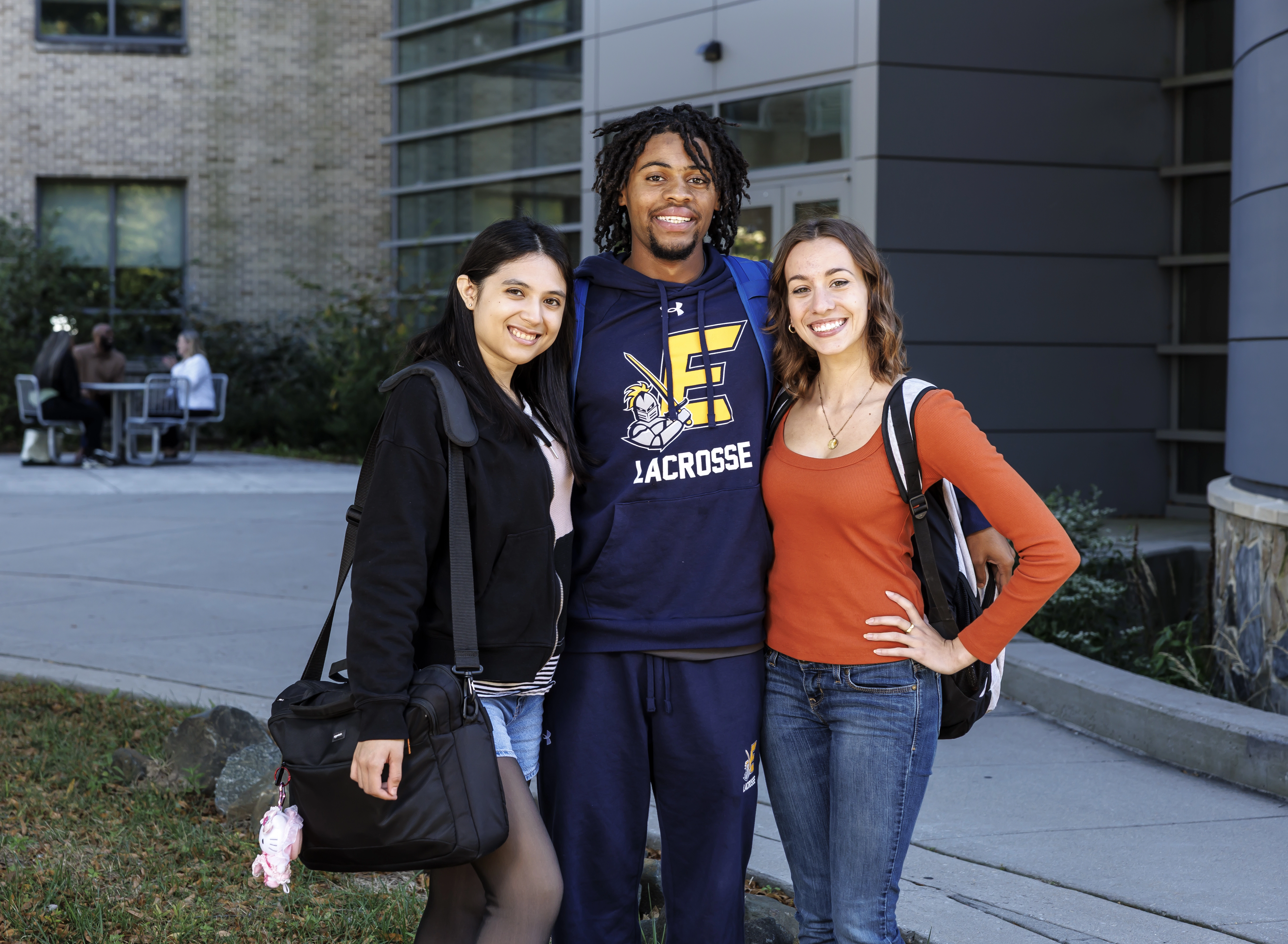 Three students stand outside of the Student Services Center.