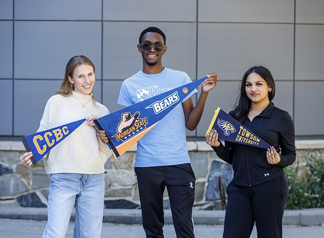 A CCBC graduate stands on the Commencement stage holding her diploma.