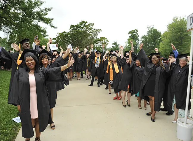 Students stand in two lines all dressed in their commencement garb.