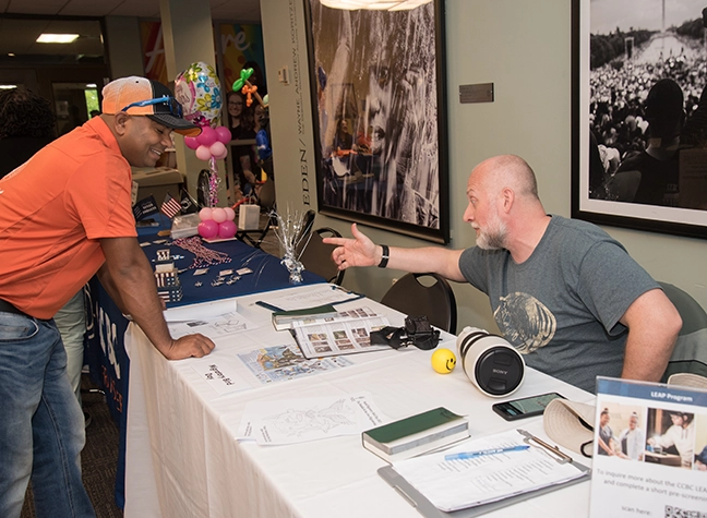 A volunteer at CCBC's LEAP table helps a student learn more about the program.