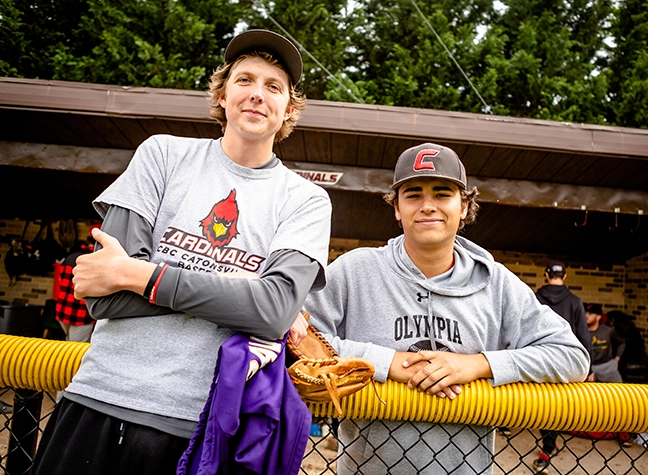 Two Cardinals baseball players stand on the sideline during practice.