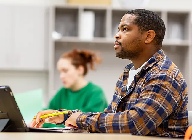 Male student taking notes in class