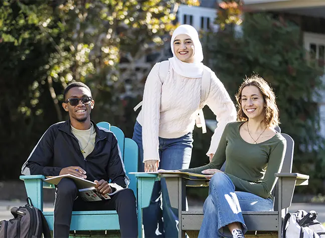 Three students sitting outside on campus, on a bright a sunny day