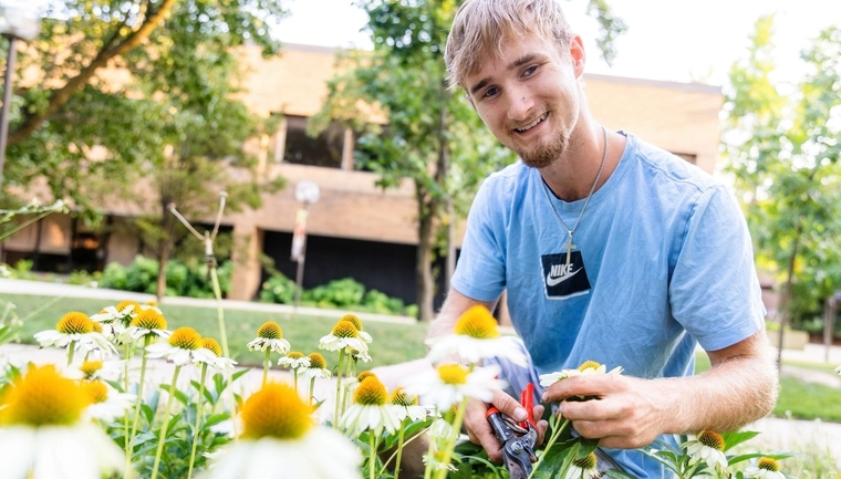 Student is sitting in a field of flowers holding a clipper