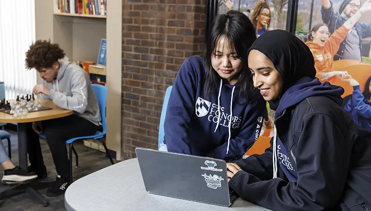 Two students working on a laptop