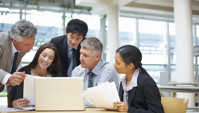 Group photo of people reviewing information on a laptop.
