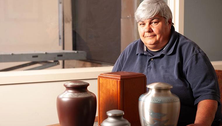 Mortuary Science faculty member standing by an assortment of urns