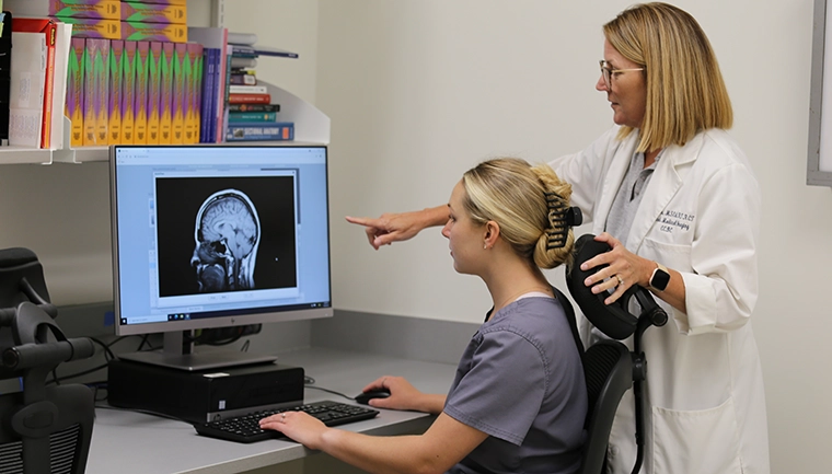 Student and faculty reading a scanned image of a head CT