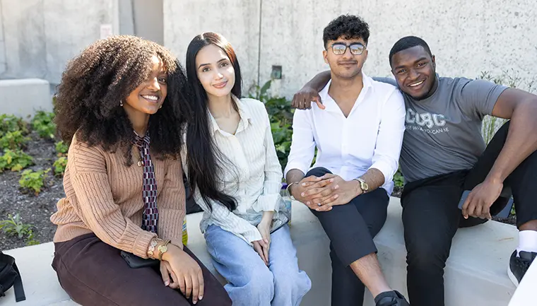 Four students sit together, Safia is in the middle.