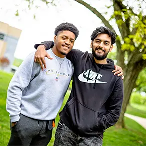 Two students standing outside on a sunny day