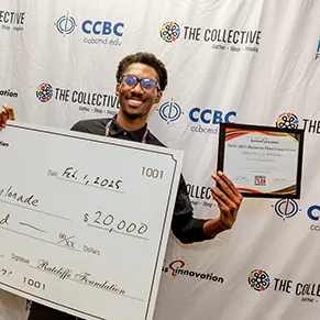 Winner of the 2024-2025 Annual Business Plan Competition holding up and oversized check for $20,000.