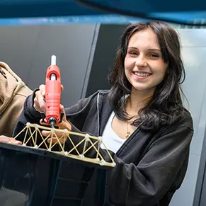 A ECAP student in PTECH works on gluing together an architectural structure as part of an engineering course.
