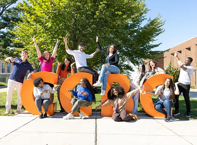 The 2024 Fresh Faces cohort gather around big orange letters that read "CCBC."