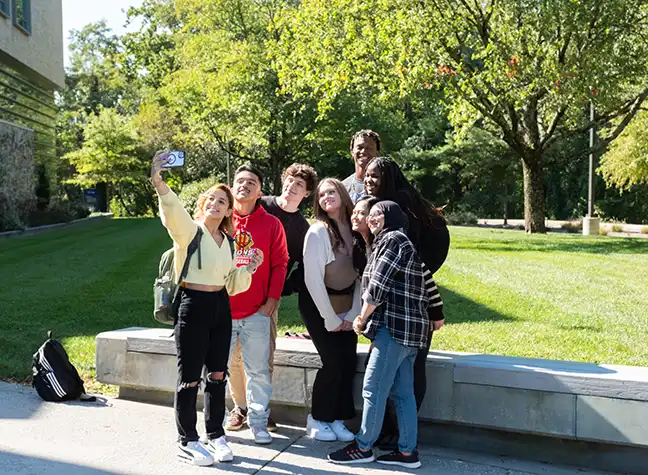 Group of students taking a selfie outside on a bright and sunny day.