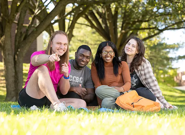 Four students from the 2024 Fresh Faces cohort sit outside on a picnic blanket.