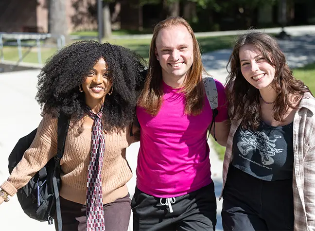 Three students walking around campus on a sunny day
