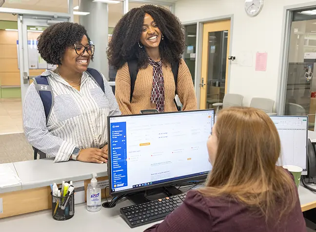 Staff member assisting two students behind the counter