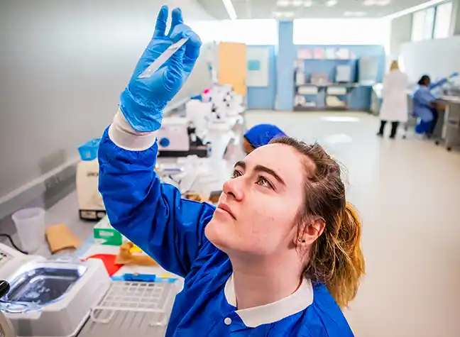 woman looking through microscope