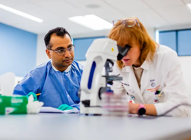 Health Professions Student looking into a microscope