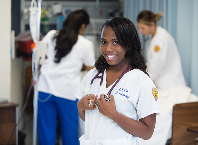 Nursing student in foreground with two students working in background