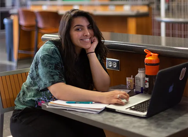 Female student sitting in cafe working on her laptop
