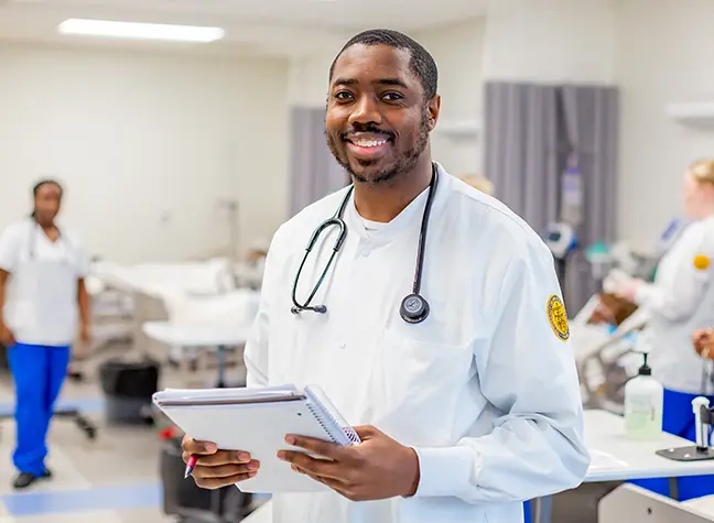 Nursing student in foreground with two students working in background