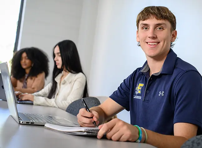 Male student in classroom on his laptop
