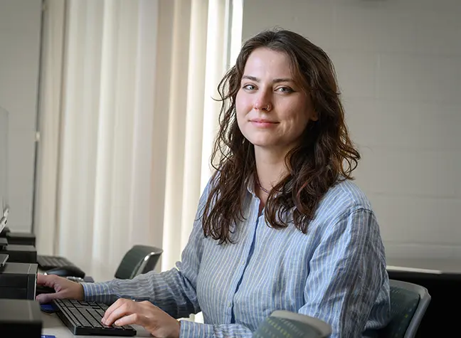 A woman in the cybersecurity field sits in front of a computer.
