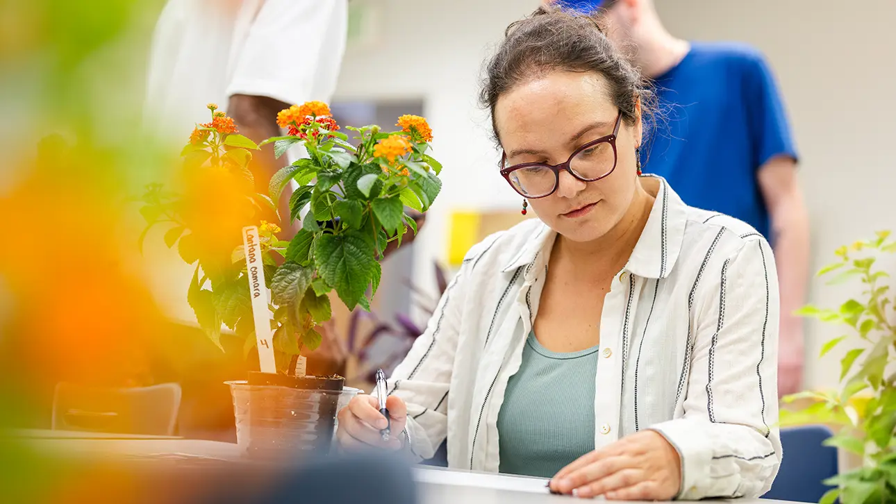 Student studying a flowering plant