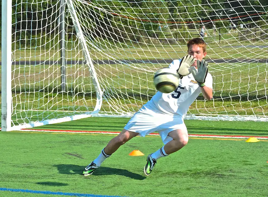 Soccer goalie in goal blocking shoot